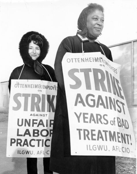An Asian American and an African American woman wear signs that indicate that they are on strike against Ottenheimer for poor treatment and unfair labor practices, December 1, 1966.