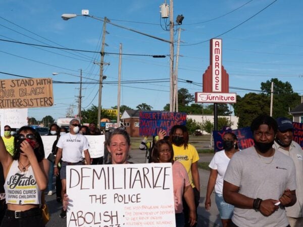Photograph of Black Lives Matters protesters walking down a street holding up signs expressing solidarity and demanding change.