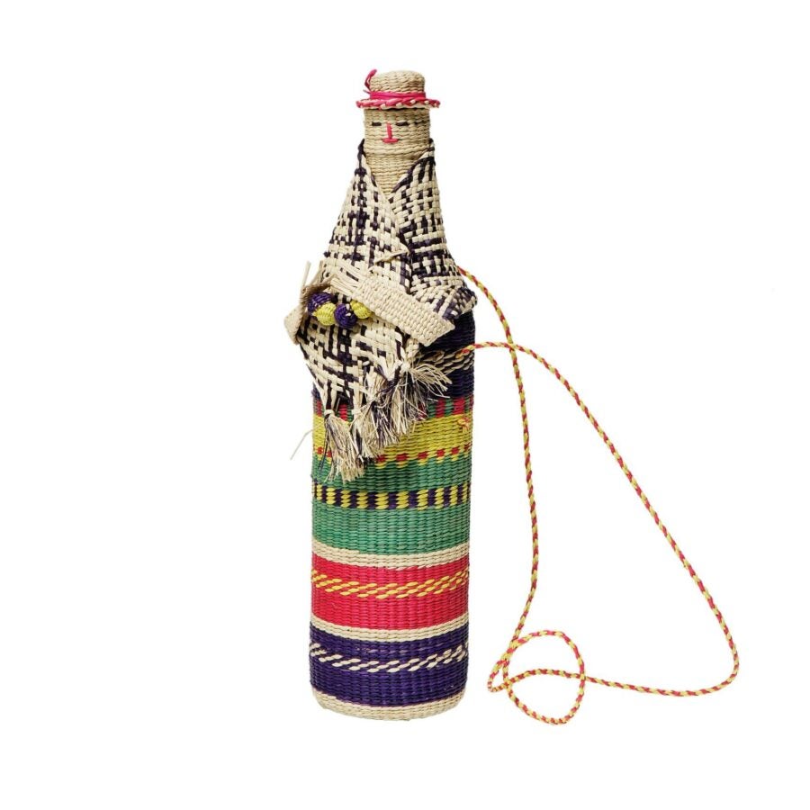 A bottle-shaped figure wrapped in colorful woven fabric with patterns and textures, decorated to resemble a person wearing a hat and shawl.