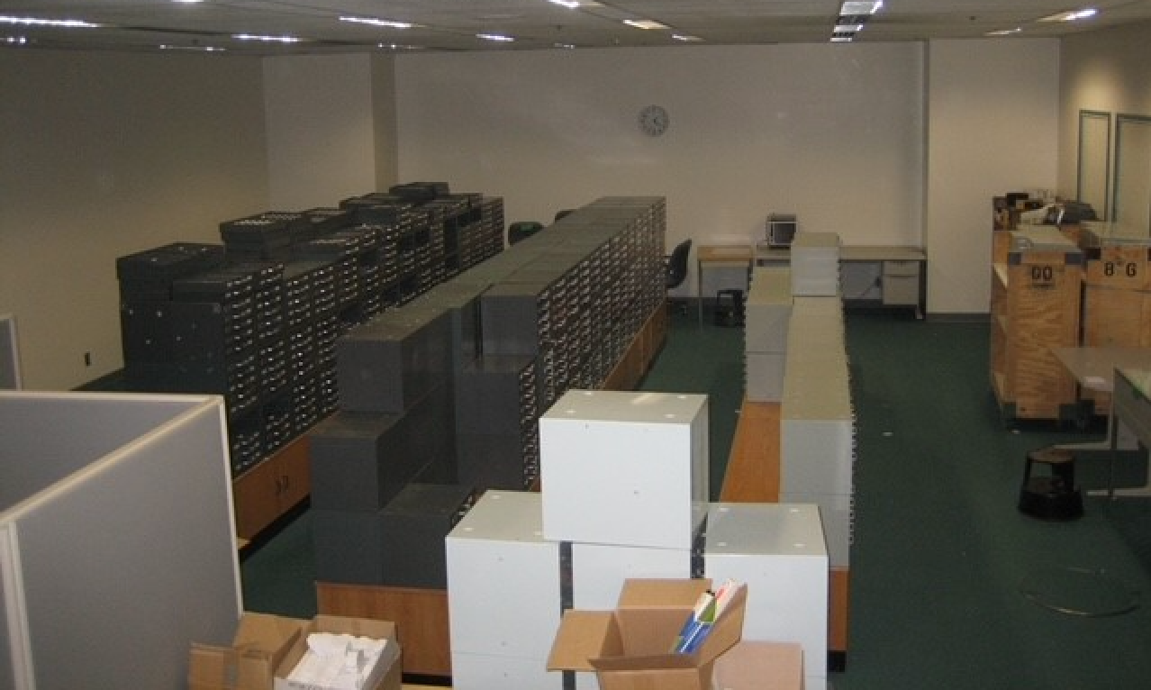 A room with rows of filing cabinets and desks, suggesting a workspace or archive storage area being cleared out.