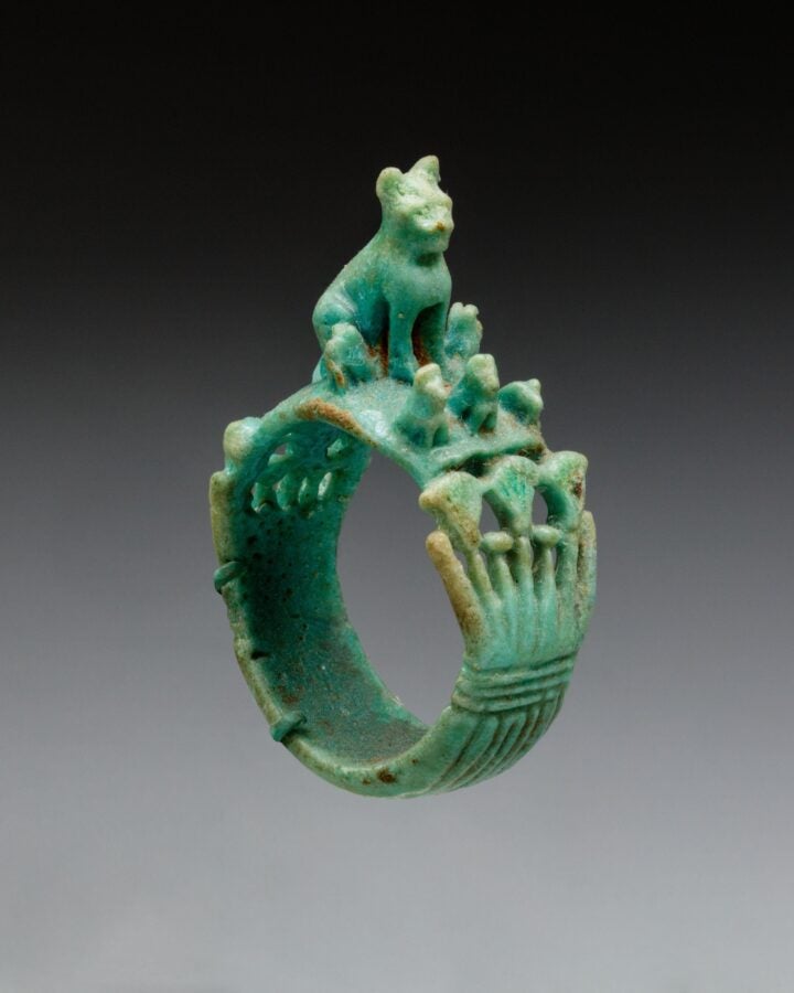 Ancient green ring topped with a seated cat and a row of tiny kittens along the band.