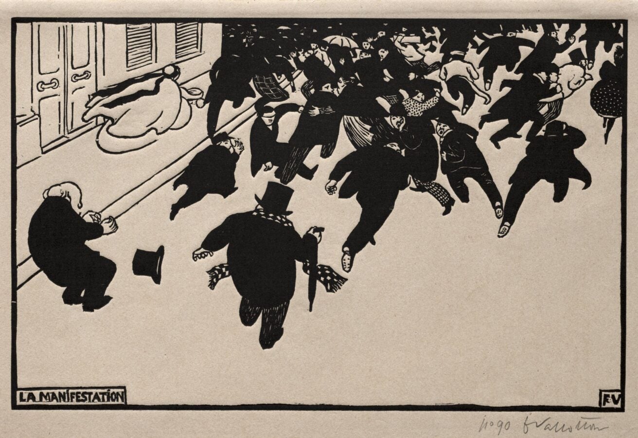 Black-and-white print of a street demonstration: a dense crowd surges down a sidewalk toward two well-dressed men; caption reads ‘La Manifestation.’