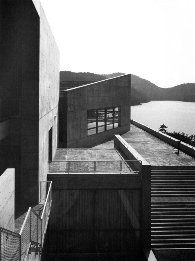 A black and white image of a building featuring prominent stairs leading to its entrance.