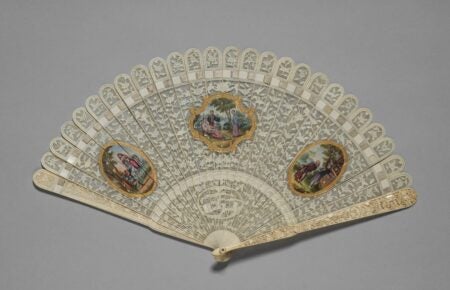 An intricately designed Brisé Fan from the 1800s, featuring carved and pierced ivory sticks adorned with floral patterns. The fan includes three painted medallions in a European style, depicting elegant scenes of figures in classical attire. The medallions are framed with gilded details, and the sticks are held together by a delicate white silk ribbon, with an iron pin at the pivot point. The craftsmanship reflects the decorative art style of the time, showcasing both artistic and functional beauty.