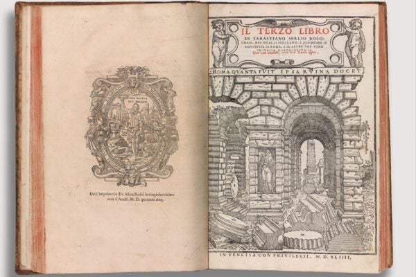 An open Renaissance-era book featuring architectural illustrations and decorative typography. The right page displays the title Il Terzo Libro by Sebastiano Serlio, with an elaborate engraving of Roman ruins, including arches, statues, and scattered architectural fragments. The left page contains a detailed emblem with Latin inscriptions, framed by intricate ornamentation.