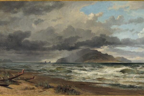 A dramatic seascape by Nicholas Chevalier showing storm clouds over Cook Strait, New Zealand. The waves are crashing against a sandy shore where two Māori-style wooden canoes rest abandoned. Distant rain veils an island under a burst of sunlight breaking through the clouds.