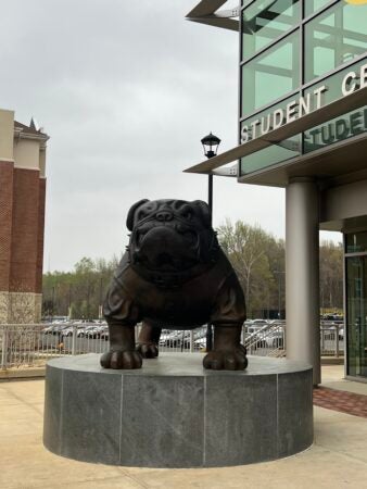 The Bowie University Mascot bronze statue is a bulldog sitting on a large round grey marble plinth.