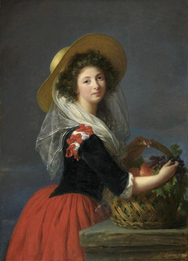 Oil painting of a young woman in a wide straw hat and red skirt, turning toward the viewer while holding a basket of fruit; soft blue-gray background and gentle, luminous light. (Élisabeth Louise Vigée Le Brun, 1784)