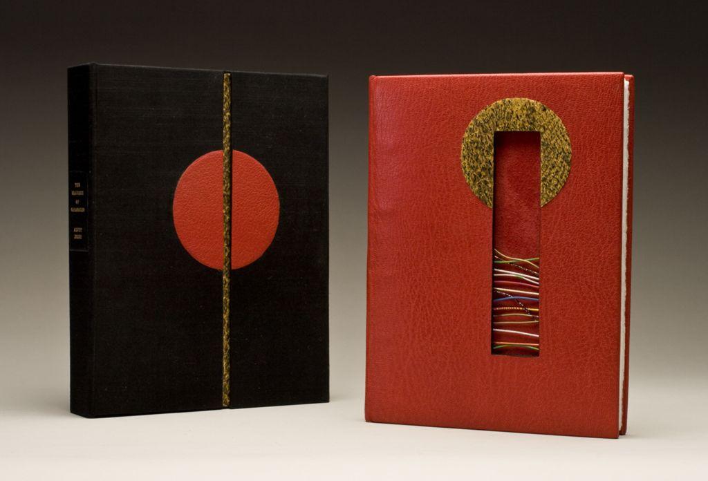 A pair of artist’s books with red and black leather covers featuring geometric cutouts and circular motifs, designed for “The Drawings of Caravaggio.”