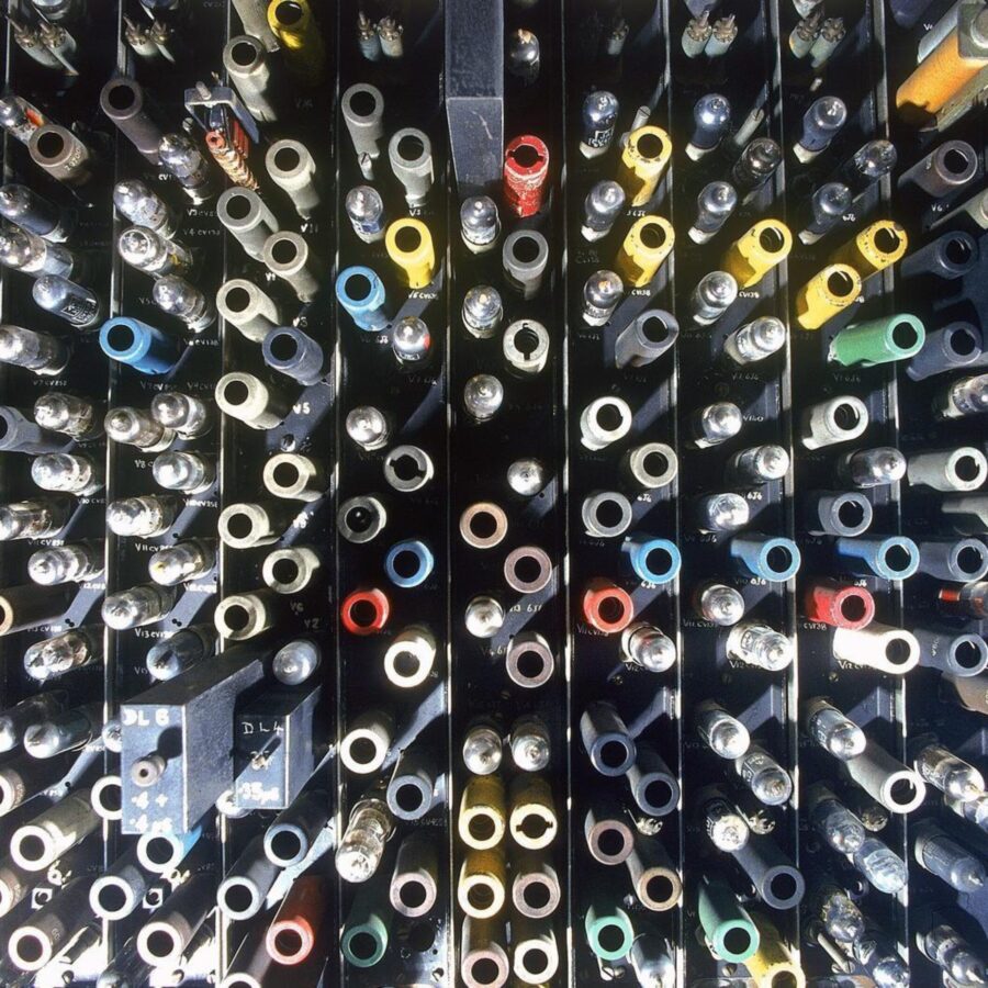 Close-up of an early computer mainframe filled with colorful cables and metal components arranged in rows.
