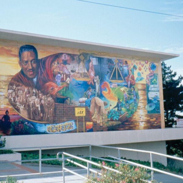 Colorful mural on a building wall depicting Thurgood Marshall surrounded by scenes representing justice, education, and community progress.