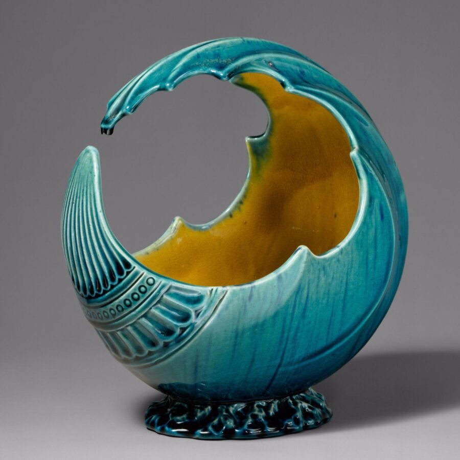Decorative ceramic vessel shaped like a curling wave, glazed in turquoise blue with a yellow interior.