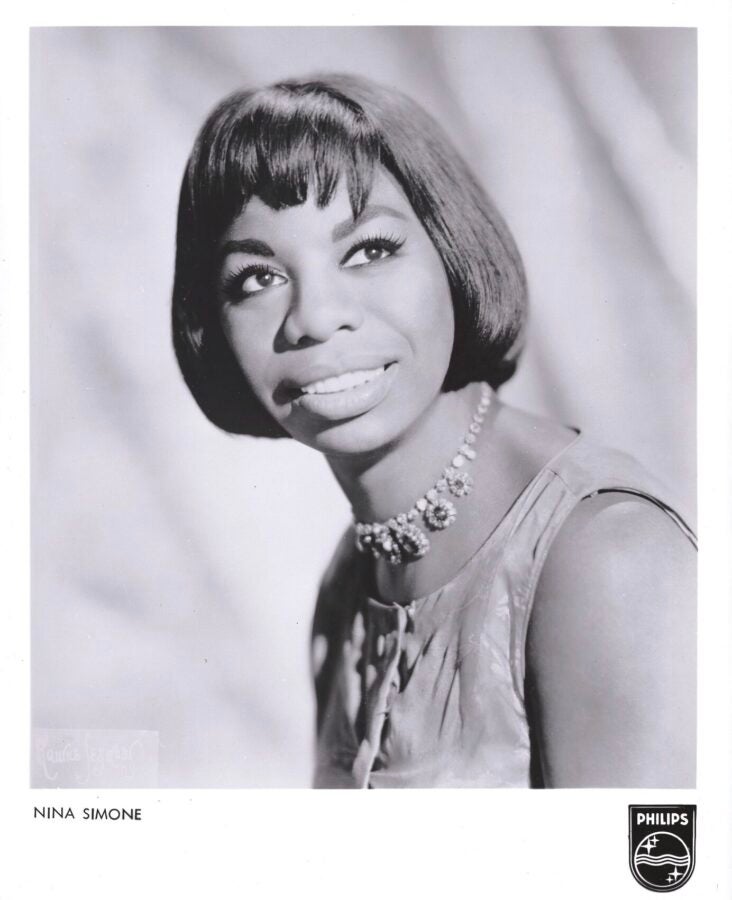 Black-and-white studio publicity portrait of a woman with a bob haircut and jeweled necklace gazing slightly upward; printed text at the bottom reads “NINA SIMONE” with a Philips logo.