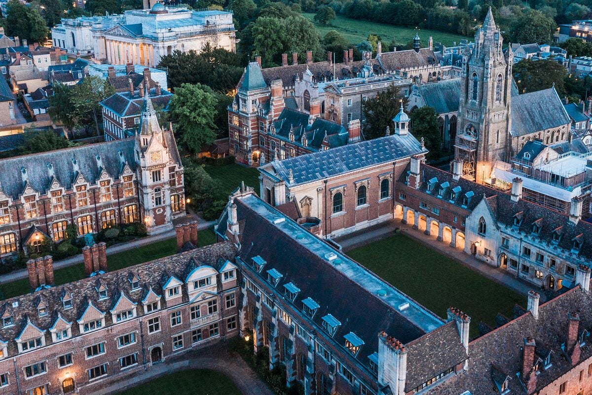 Aerial view of historic university buildings and courtyards surrounded by green trees in the United Kingdom.