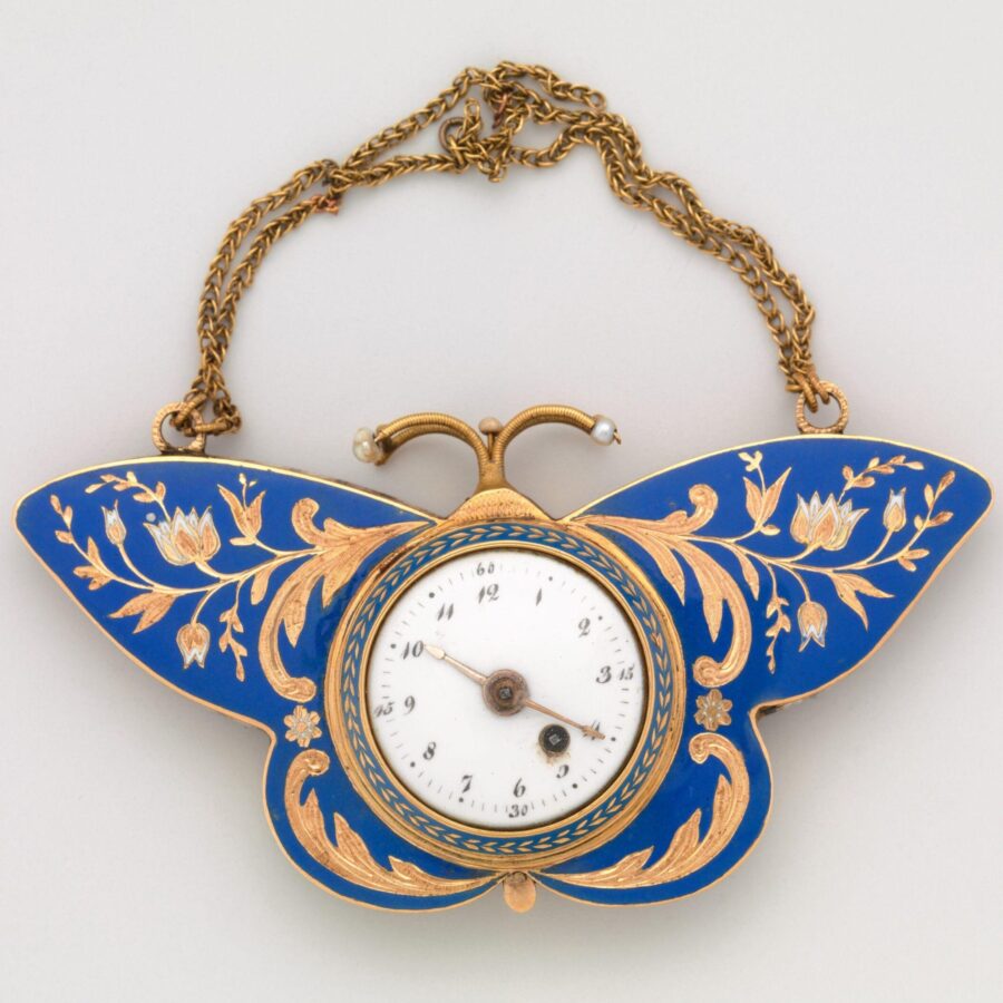 An ornate 19th-century butterfly-shaped pocket watch with blue enamel wings decorated with gold floral designs and a small clock face in the center.