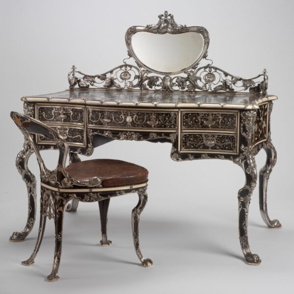 An ornate black and silver writing desk with intricate inlay, paired with a matching decorative chair and an attached mirror.