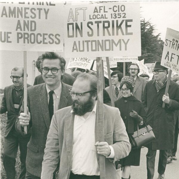 A group of striking workers marches with signs calling for autonomy, amnesty, and due process.