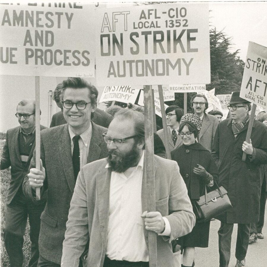 A group of striking workers marches with signs calling for autonomy, amnesty, and due process.
