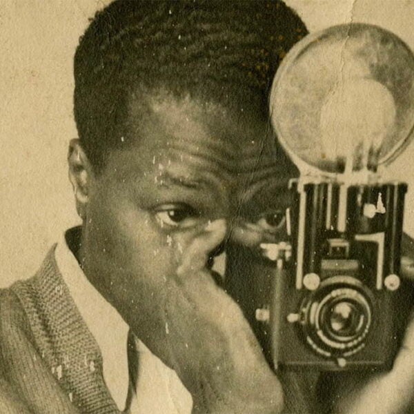 Vintage portrait of a Black man holding a camera up to his eye as he prepares to take a photograph.