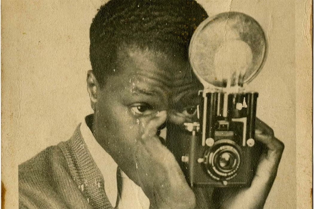 Vintage portrait of a Black man holding a camera up to his eye as he prepares to take a photograph.