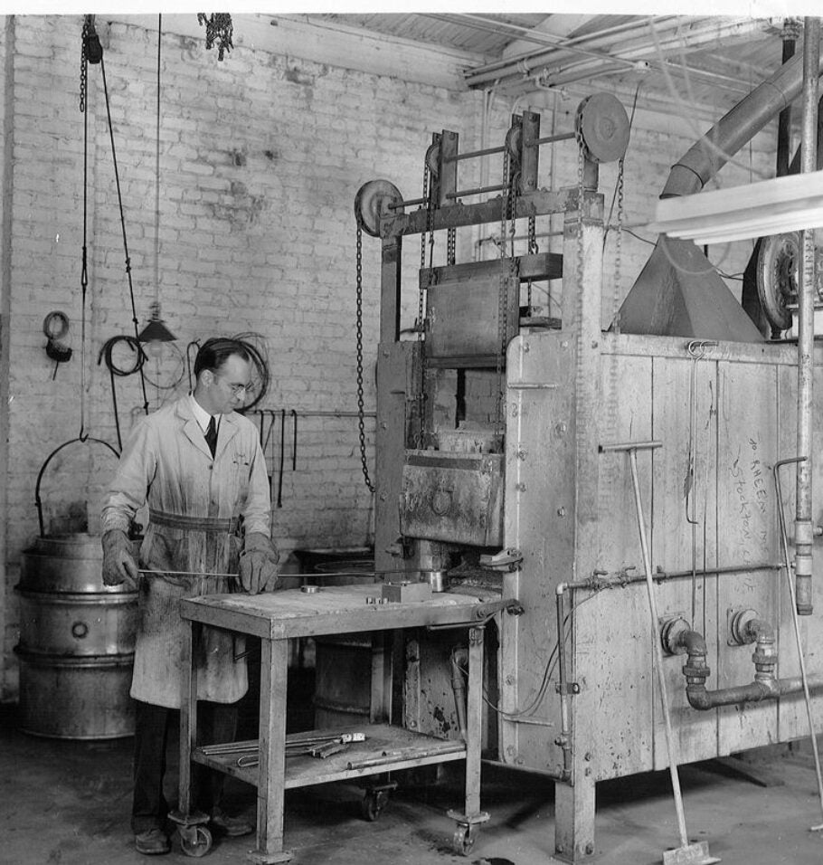 Black-and-white photograph of a man operating industrial machinery in a workshop.