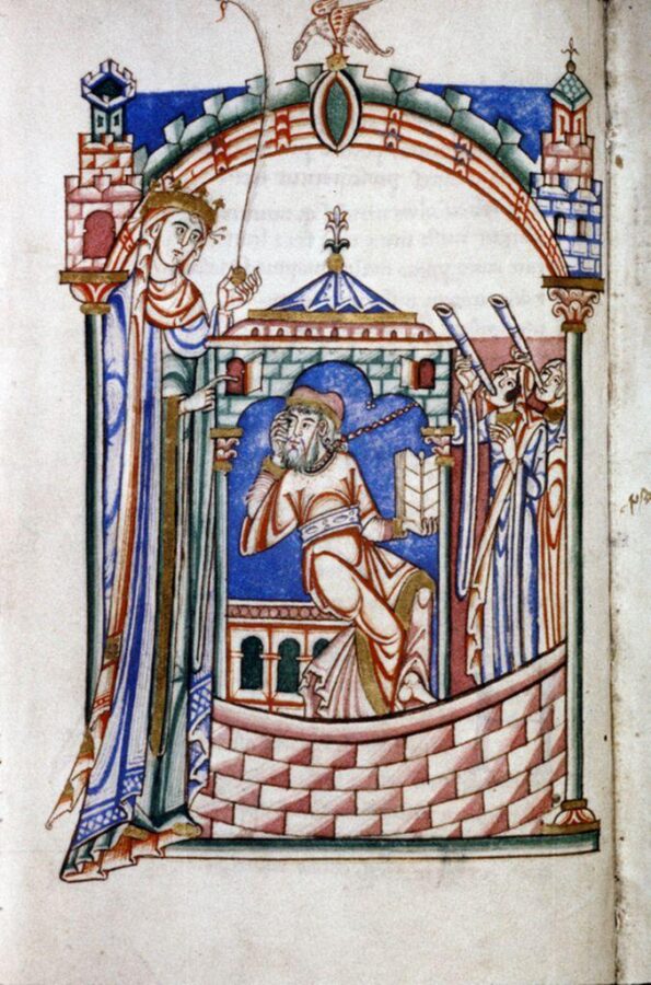 Twelfth-century manuscript drawing: Boethius, bearded and chained by the neck, sits in a walled prison holding an open book, hand to his cheek, while a tall crowned figure of Philosophy stands at left pointing toward him and two figures at right blow long horns.