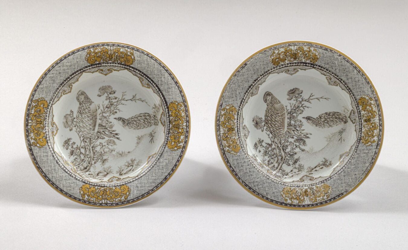 Pair of round porcelain plates decorated with finely drawn quail among flowering plants. Gold chrysanthemum motifs and geometric borders frame the central scenes.
