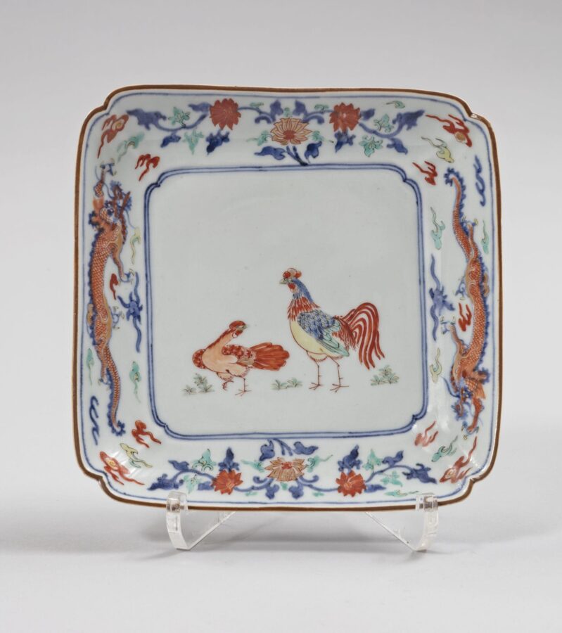 Square porcelain dish with rounded corners featuring a rooster and hen in the center. The border is decorated with blue dragons, flowering vines, and red, green, and yellow accents.