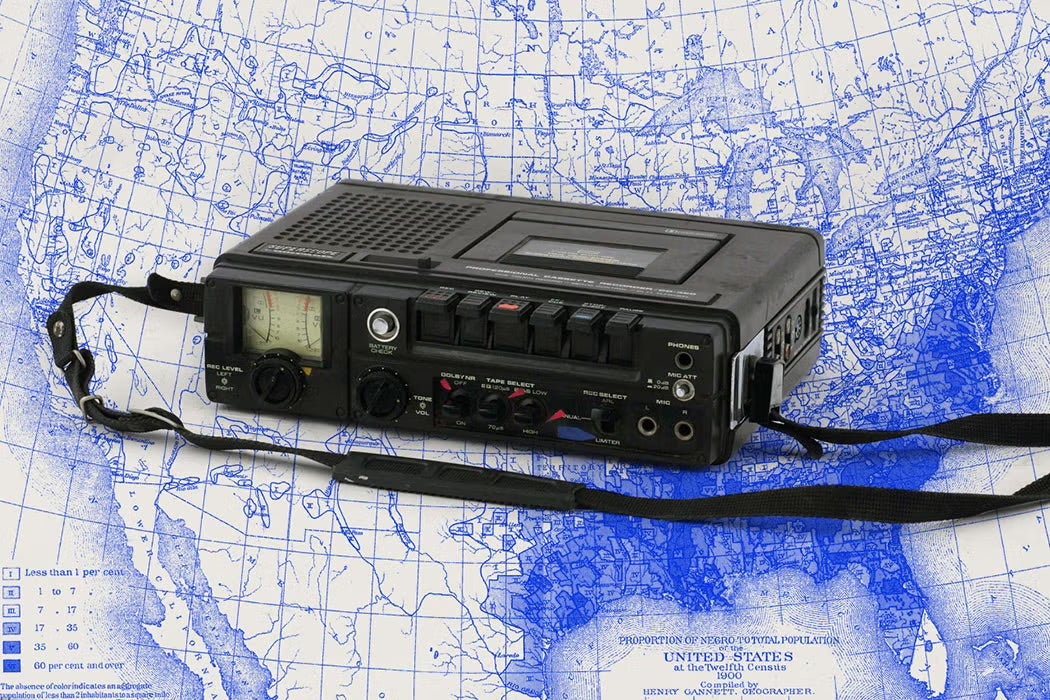 Portable cassette recorder resting on a blue-and-white historical map of the United States, with its shoulder strap extending across the image.